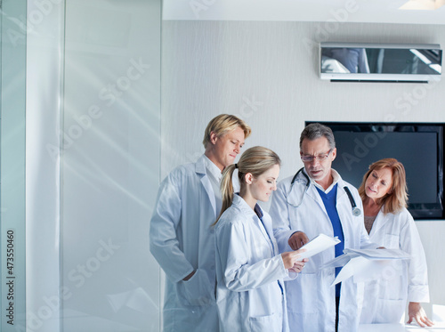 Senior doctor explaining reports to male and female healthcare workers in hospital photo