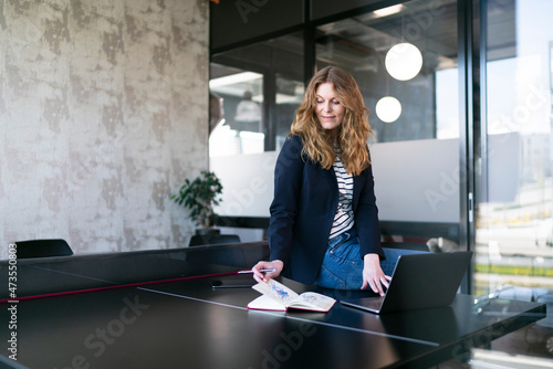 Female professional searching in diary while sitting on table by laptop at office photo