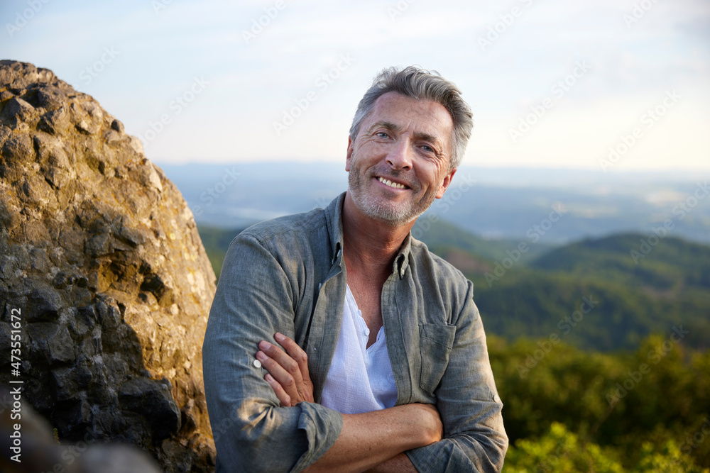 Male hiker smiling with arms crossed at sunset Male hiker smiling with arms crossed at sunset