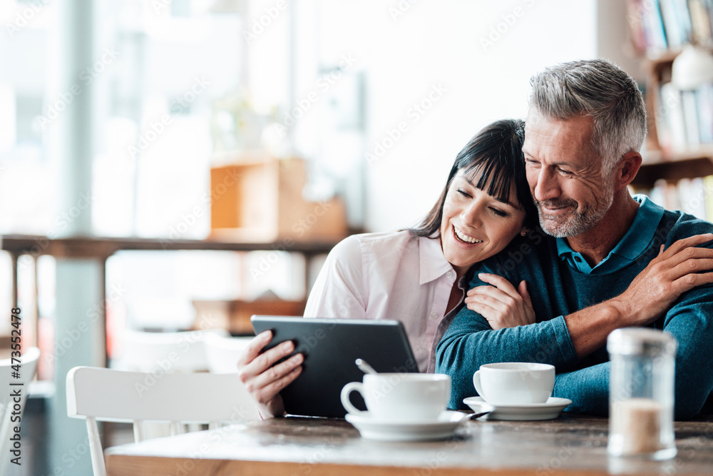 Business couple smiling while using digital tablet at cafe Business couple smiling while using digital tablet at cafe