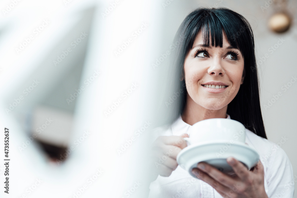 Smiling female owner with coffee cup looking away at cafe Smiling female owner with coffee cup looking away at cafe