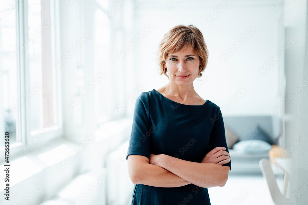 Female business professional with arms crossed standing in office Female business professional with arms crossed standing in office