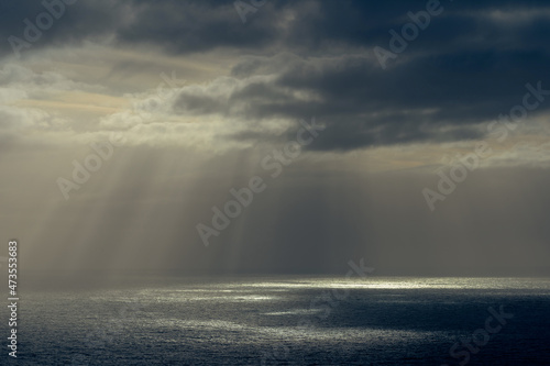Rays of sun through dark clouds at ocean. © Arild