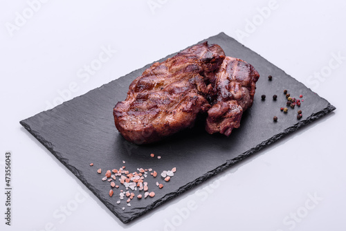 grilled beef steaks with spices on a dark cutting board