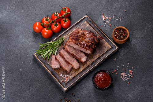 grilled beef steaks with spices on a dark cutting board