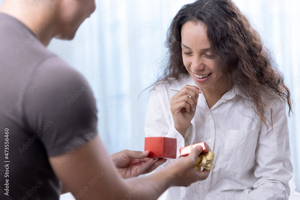 Handsome boyfriend surprises his beautiful girlfriend by giving her a present, Happy couple, Propose, Wedding anniversary, Valentine's Day. Handsome boyfriend surprises his beautiful girlfriend by giving her a present, Happy couple, Propose, Wedding anniversary, Valentine's Day.