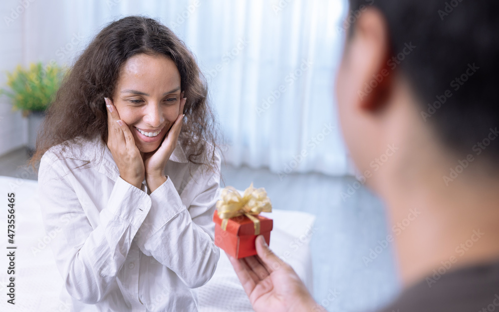 Handsome boyfriend surprises his beautiful girlfriend by giving her a present, Happy couple, Propose, Wedding anniversary, Valentine's Day. Handsome boyfriend surprises his beautiful girlfriend by giving her a present, Happy couple, Propose, Wedding anniversary, Valentine's Day.