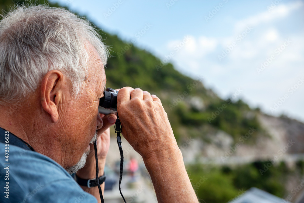 Senior man looking through binoculars Senior man looking through binoculars