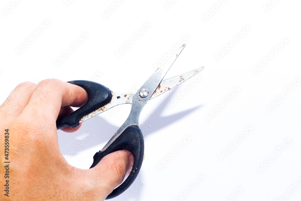 Obraz premium small black scissors in hand on an isolated white background. want to cut something