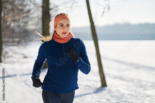 Young woman in sports clothing jogging during winter