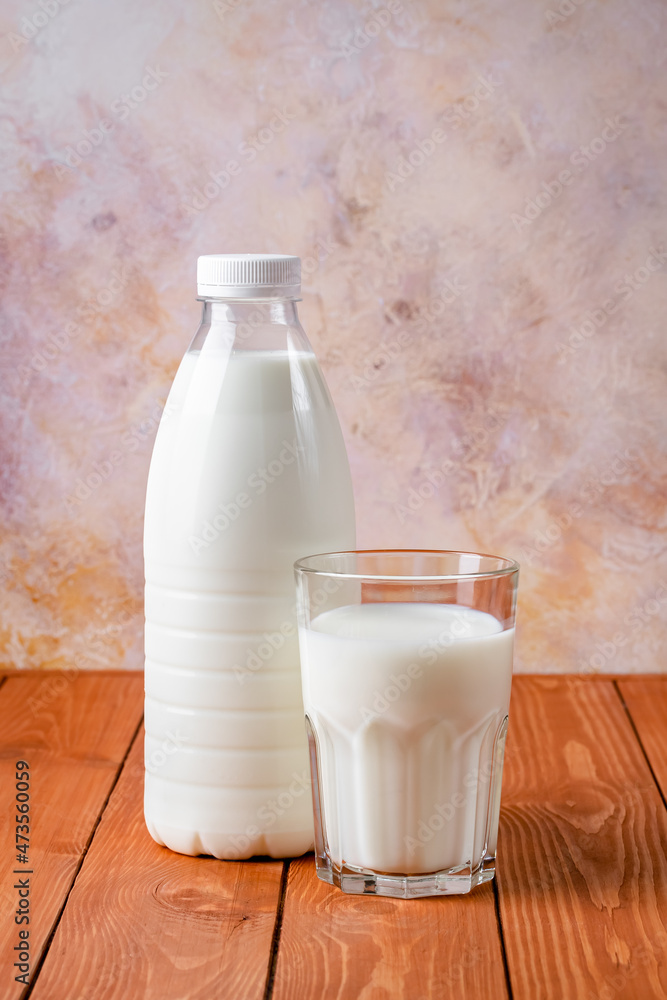 Bottle and glass of milk on a brown wooden table. Food background, cooking ingredient, drink. Healthy food, a source of calcium. Bottle and glass of milk on a brown wooden table. Food background, cooking ingredient, drink. Healthy food, a source of calcium.