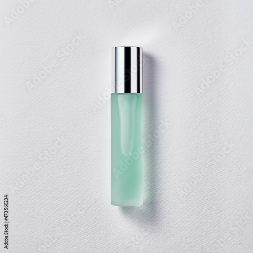 Colored cosmetic in glass bottle with chrome cap on white background