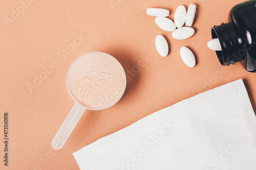 Whey protein powder in measuring spoon next to amino acid pills