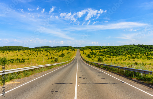 The road of regional significance rises to a hill covered with small groups of trees