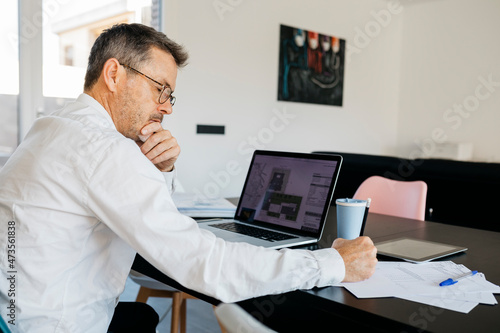 Male design professional working on business strategy at table in domestic kitchen photo