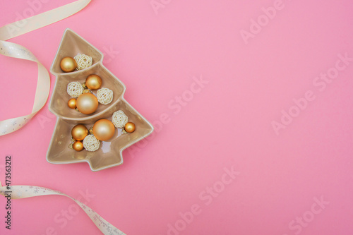 Pink background with gold balls, porcelain dish and packing tape. New Year's decoration. Background. Christmas. Spruce.