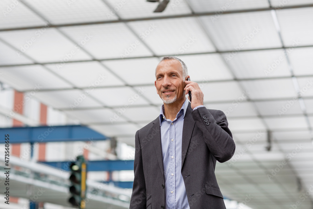 Businessman talking on smart phone at railroad station Businessman talking on smart phone at railroad station