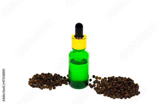 Black pepper essential oil in green glass bottle with peppercorn isolated on white background.