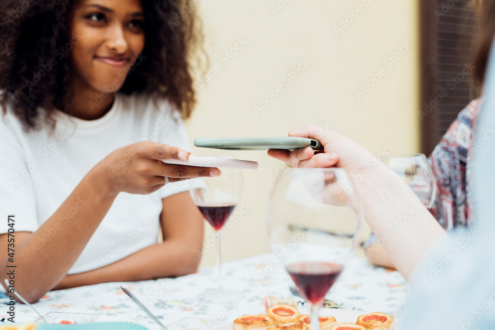 Friends sharing mobile phone while sitting by table Friends sharing mobile phone while sitting by table