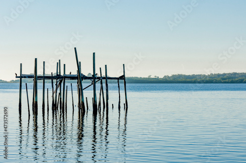 Remnants of a fish shanty in Cedar Key, Florida with blue water and sky.