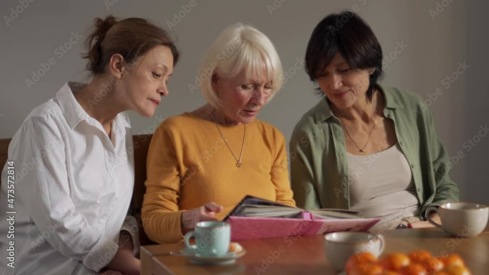 Confident mature women looking at old photos at home Confident mature women looking at old photos at home