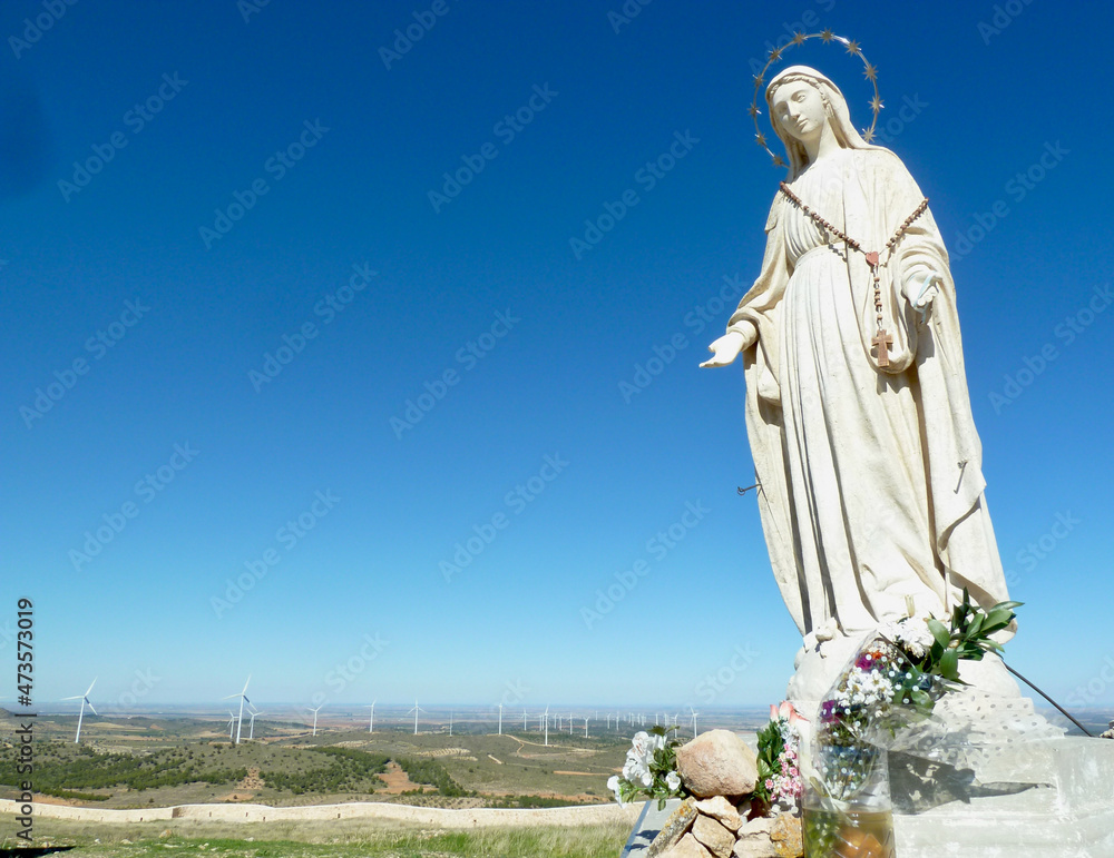 Madonna at the castle of Penas de San Pedro overlooking wind turbines in Castilla La Mancha, Spain.