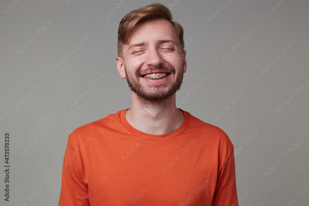 Studio portrait of young bearded man, wears casually posing over gray studio background smiles broadly and showing his teeth to the world. isolated. Studio portrait of young bearded man, wears casually posing over gray studio background smiles broadly and showing his teeth to the world. isolated.