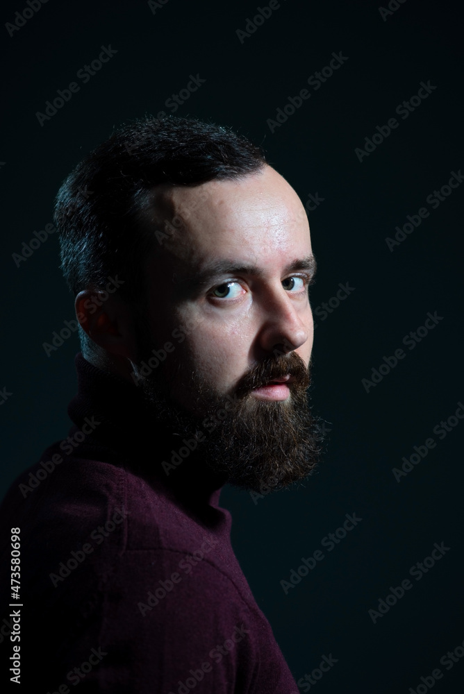 Fototapeta premium portrait of a bearded millennial guy in a burgundy sweater on a gray background