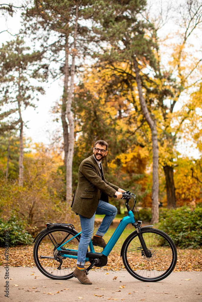 Young man with electric bicycle in the autumn park