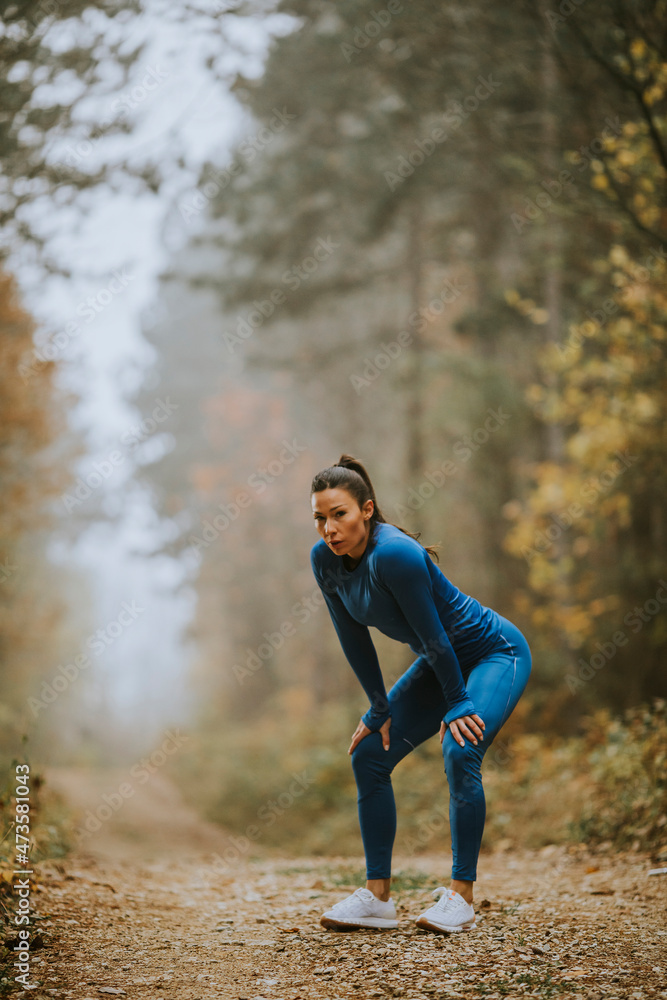 Young woman take a break during outdoor exercise on the forest trail at autumn Young woman take a break during outdoor exercise on the forest trail at autumn