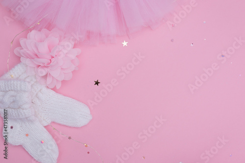 Background of baby decor and  baby supplies on pink background. Top view decoration baby socks and tutut skirt with glitter stars.  Copy space for add text. photo