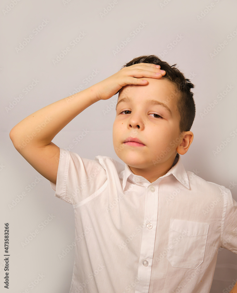 The boy adjusts his hairstyle with his right hand on top of his forehead The boy adjusts his hairstyle with his right hand on top of his forehead