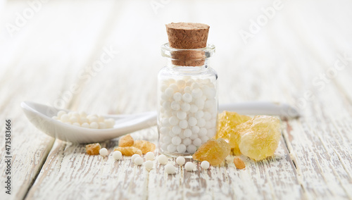 Fotografia Sulphur crystal with homeopathic globules on white wooden background