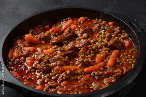 Beef stew, meat ragout with carrots, onions and green peas. Meat stew with vegetables in tomato sauce in a bowl.