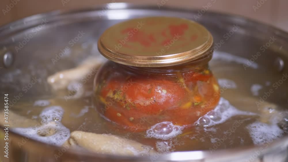 Process of Sterilizing a Jar of Pickled Tomatoes in a Saucepan of Boiling Water. Preserving jars