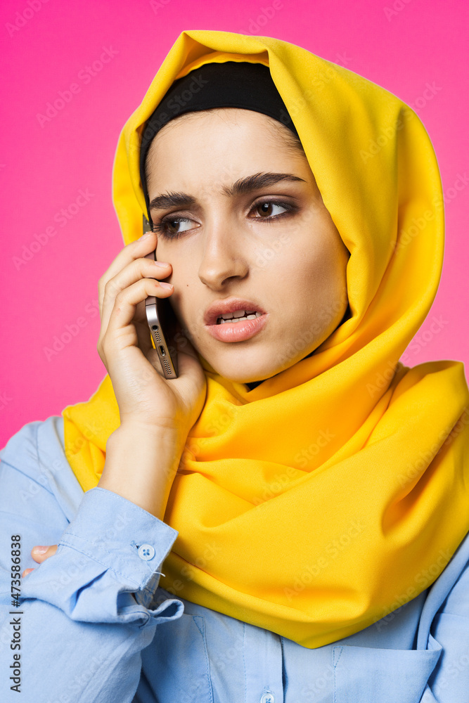 muslim woman in yellow hijab talking on the phone technology pink background muslim woman in yellow hijab talking on the phone technology pink background