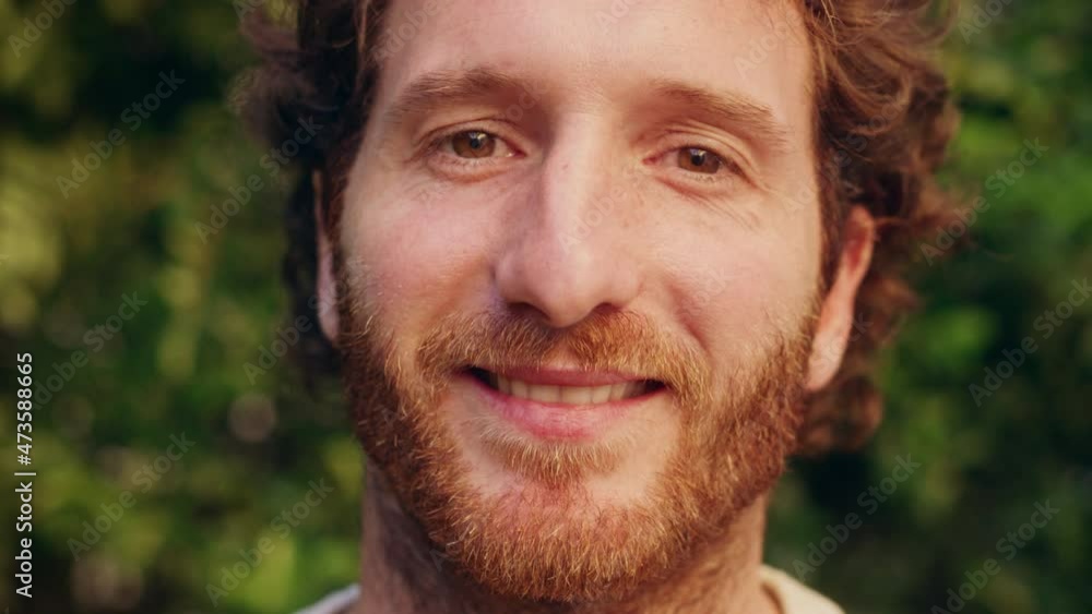 Close Up Portrait of a Happy Young Adult Male with, Brown Eyes, Curly Ginger Hair and Beard Posing for Camera. Handsome Diverse Caucasian Male Smiling on Green Nature Background. Close Up Portrait of a Happy Young Adult Male with, Brown Eyes, Curly Ginger Hair and Beard Posing for Camera. Handsome Diverse Caucasian Male Smiling on Green Nature Background.