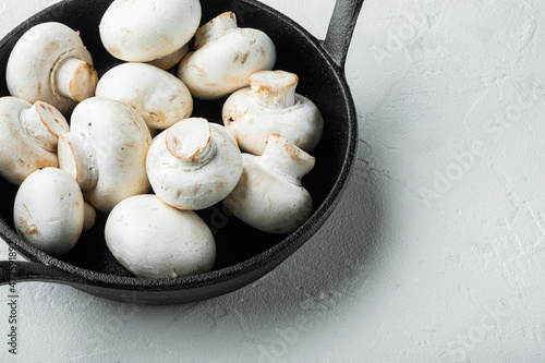 Mushroom champignon, in cast iron frying pan, on white stone surface