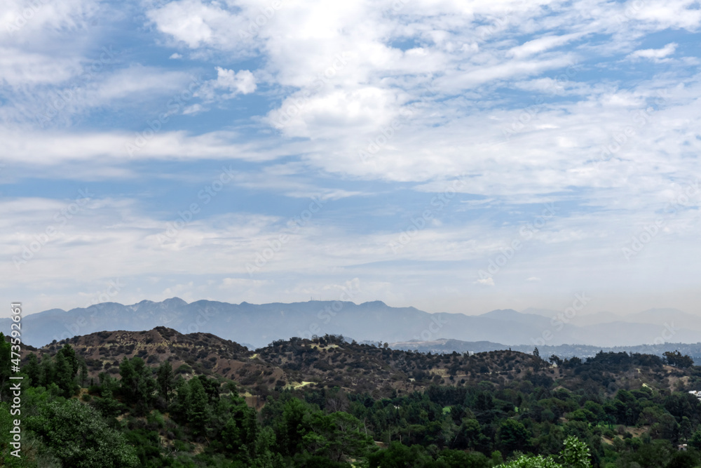 Hills or mountains covered with trees in Los Angeles area with silhouettes in the background