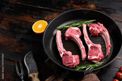 Raw fresh meat ribs, on frying cast iron pan, on old dark rustic table background, with copy space for text