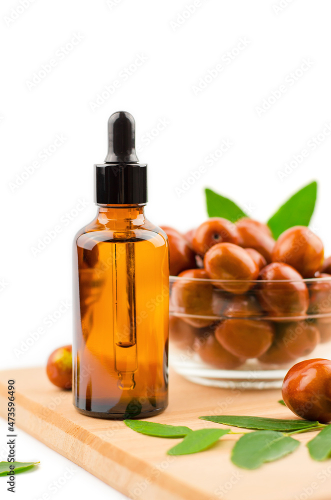 Jojoba oil bottle. Jojoba oil and fresh jojoba fruit on wooden table Jojoba oil bottle. Jojoba oil and fresh jojoba fruit on wooden table