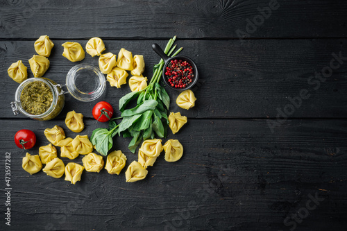 Raw Tortellini with basil and pine pesto, on black wooden table background, top view flat lay, with copy space for text