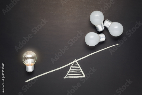 Only one light bulb that is glowing has more weight than many light bulbs that are not, less is more, success small idea, inspire and clarify concept photo