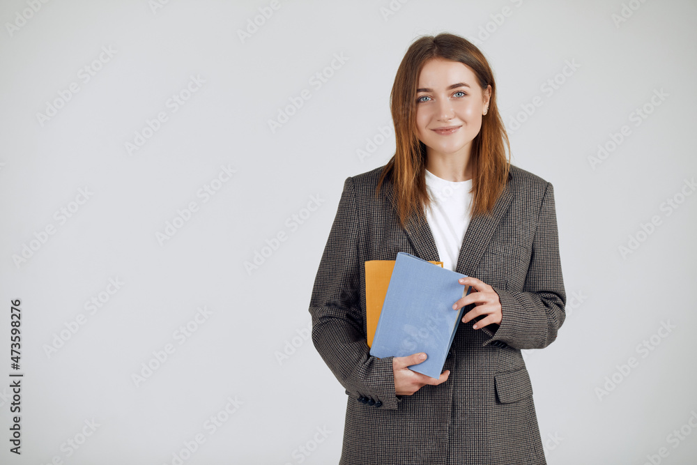 Attractive business woman looking at camera and carrying some books Attractive business woman looking at camera and carrying some books