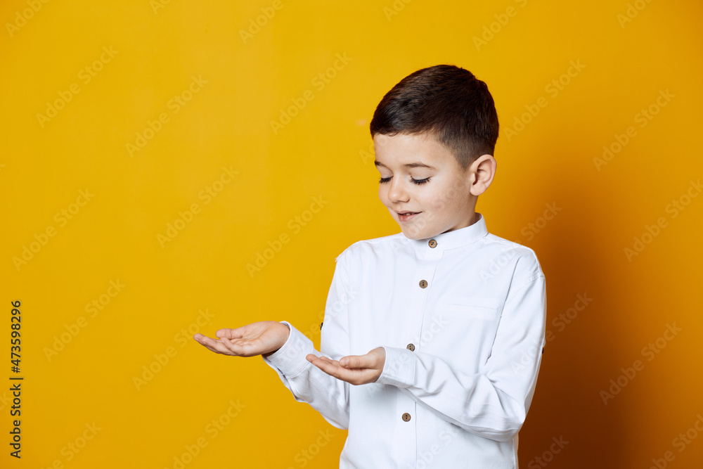 Portrait of a smiling kid wearing white shirt reaching his hands like he is holding something Portrait of a smiling kid wearing white shirt reaching his hands like he is holding something