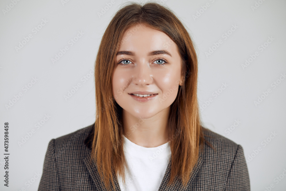 Close up portrait of a young smiling business woman looking at camera wearing grey blazer. Close up portrait of a young smiling business woman looking at camera wearing grey blazer.