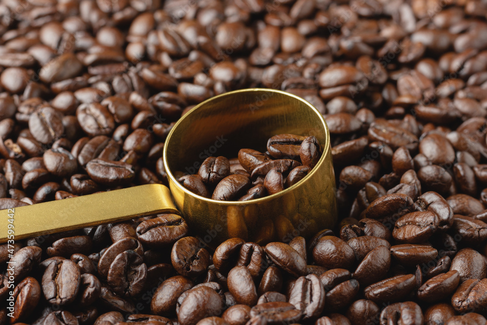 Naklejka premium Coffee beans in golden spoon.