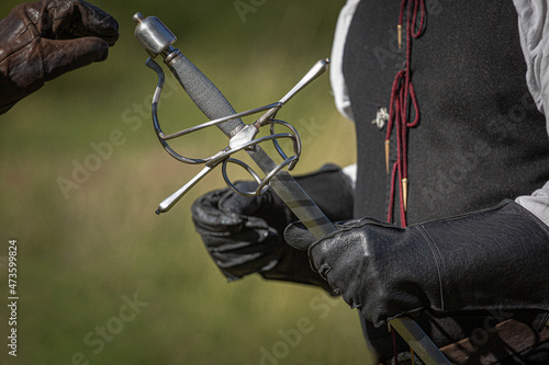 hand in leather gloves taking hilt of sword during historical re-enactment