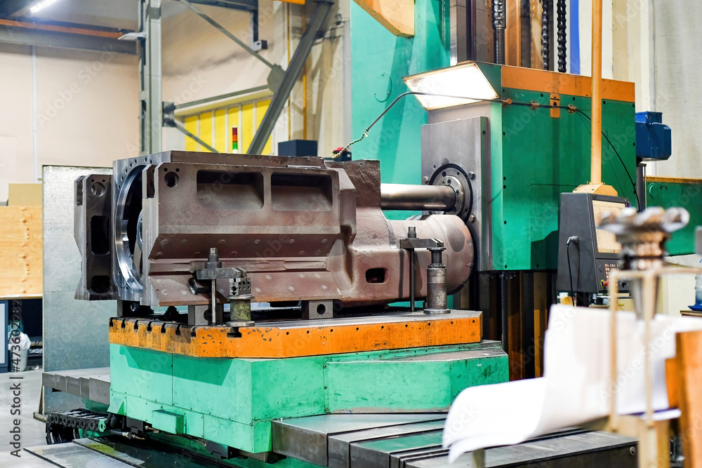 An unfinished metal part is on the machine in the workshop.