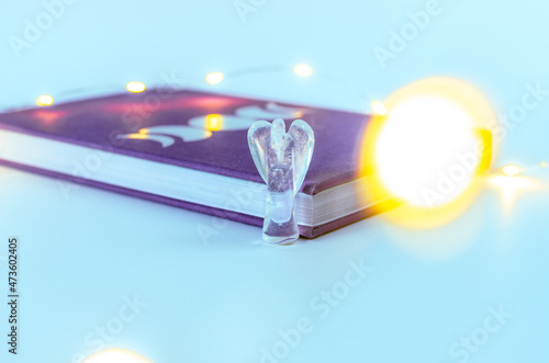 Close up angel crystal from clear quartz near a moon journal with Christmas lights and incense on background. Concept: spiritual self care practices